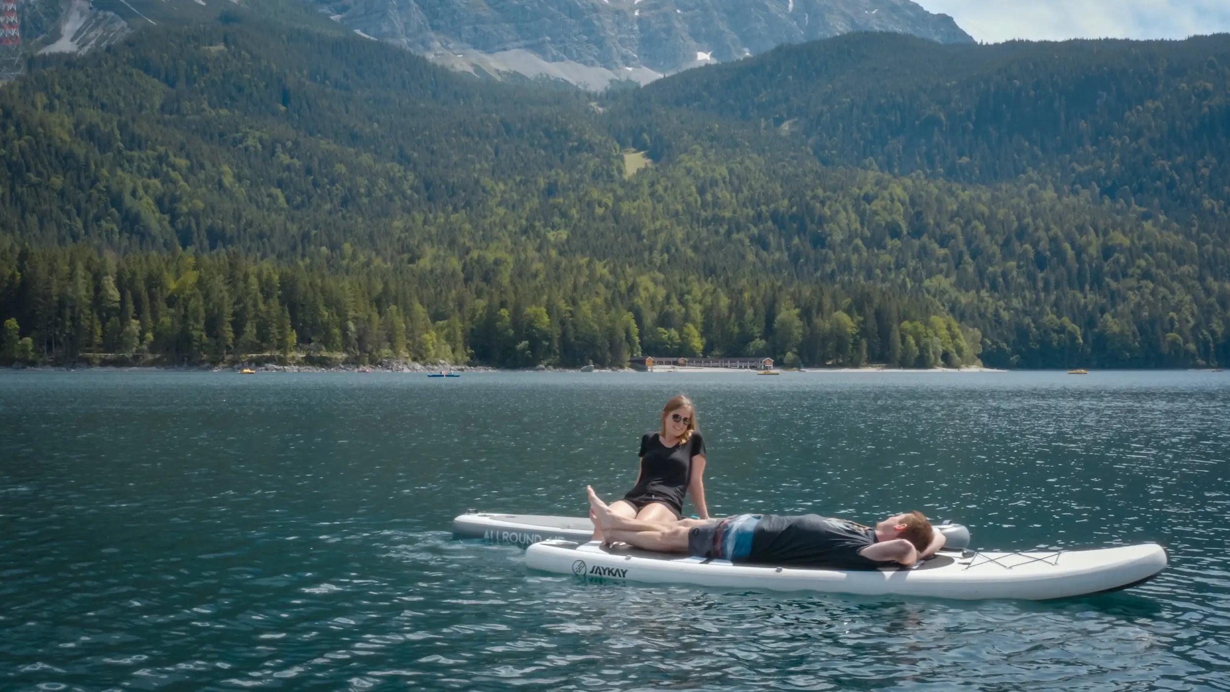 Menschen liegen auf SUP-Board im See