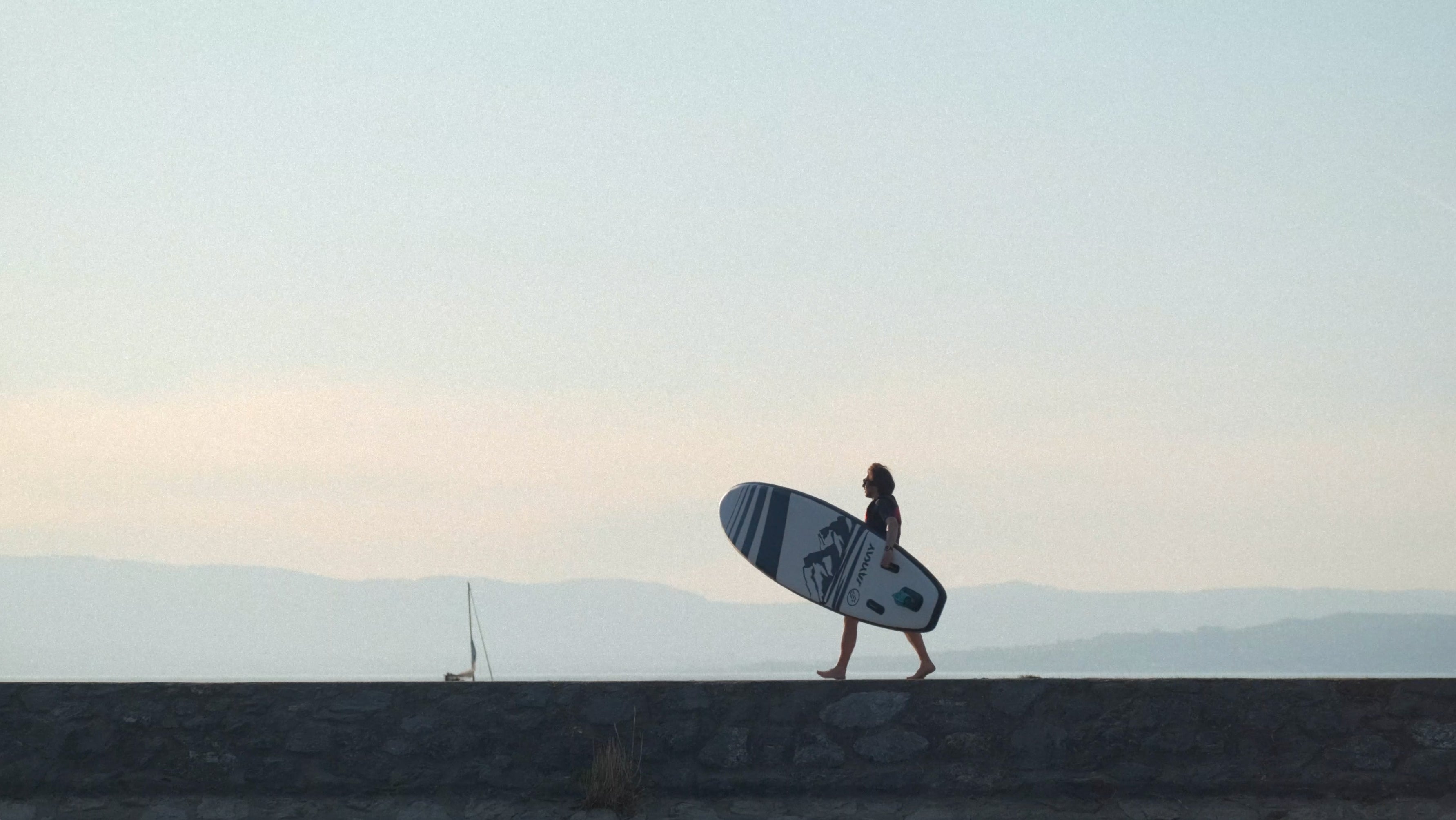Donna che trasporta una tavola da SUP davanti a un paesaggio