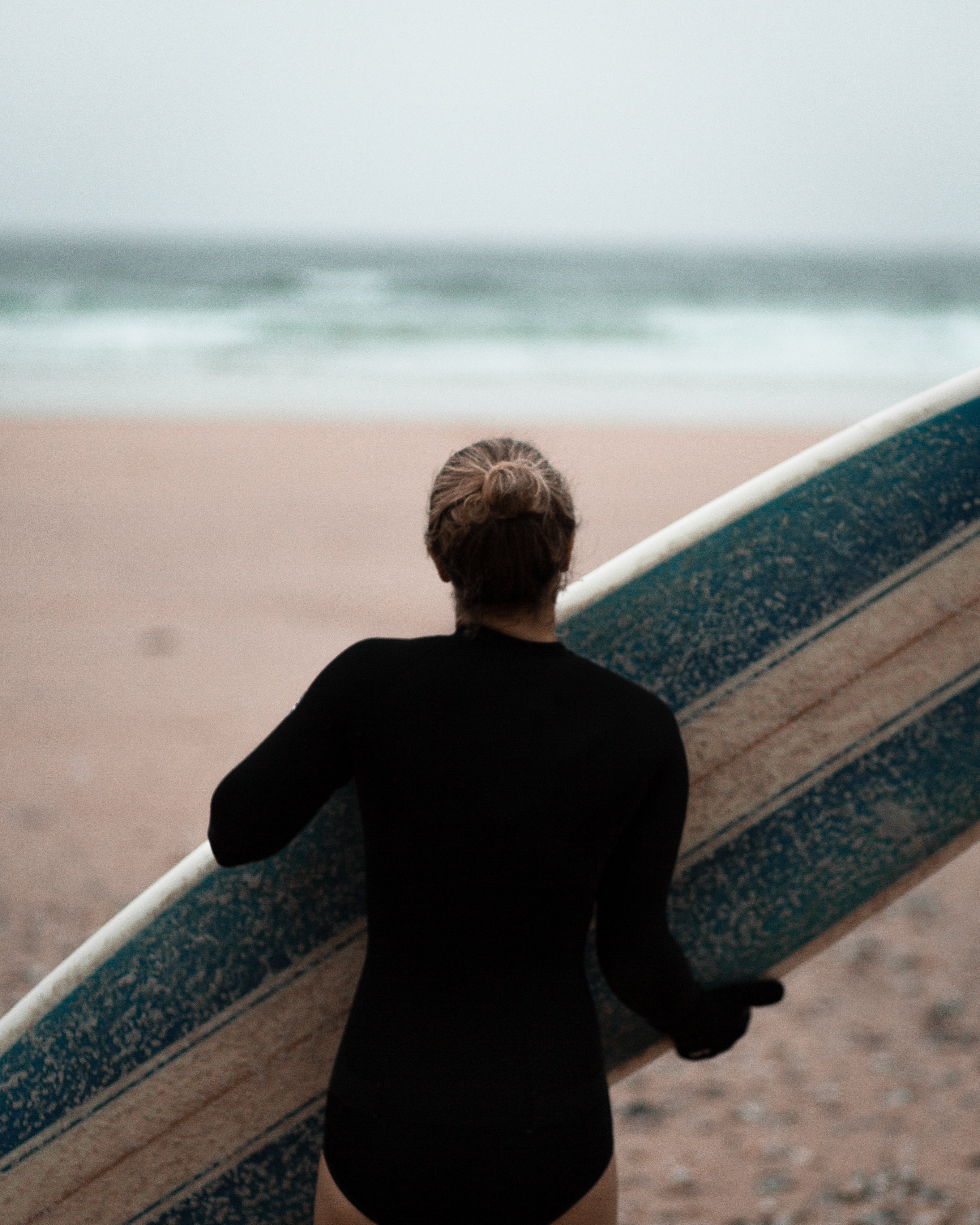 Mann trägt Surfboard am Strand