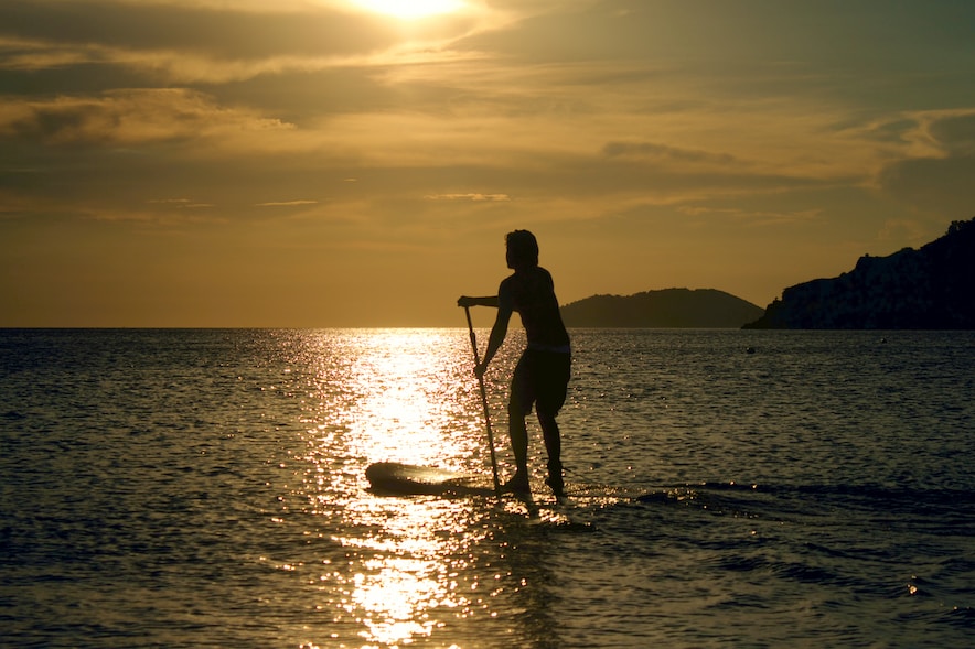 Une femme sur une planche de surf au coucher du soleil